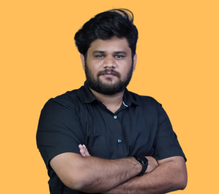 This professional portrait features Rayan Sahad, confidently posing with his arms crossed against a vibrant orange background. Dressed in a sleek black shirt and wearing a minimalist wristwatch, Rayan radiates authority and focus—qualities that define him as the best digital marketer in Kochi